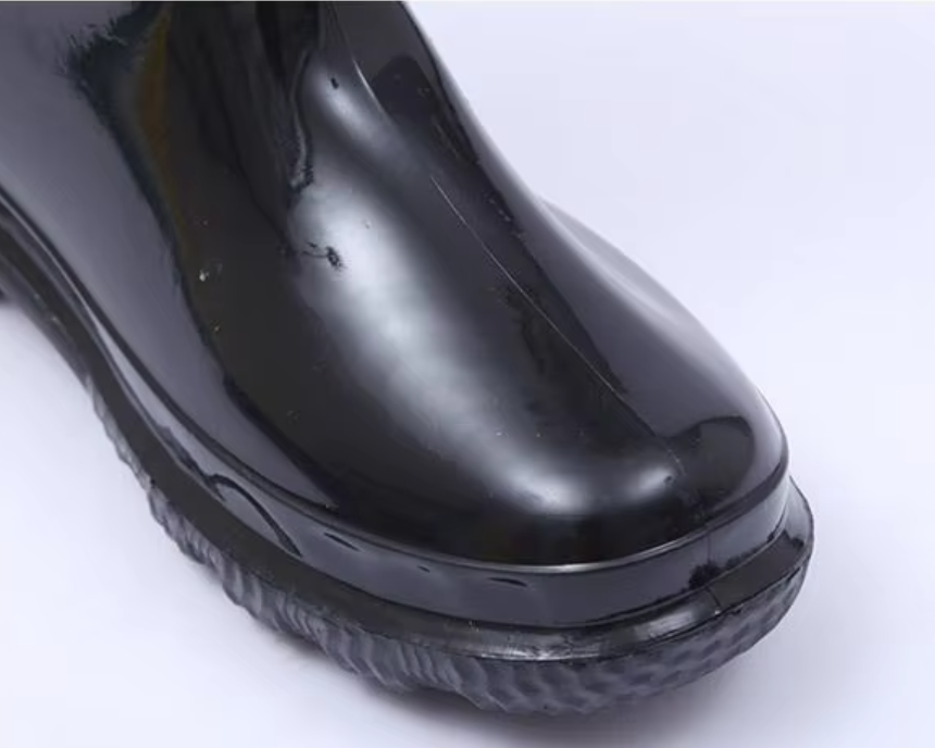 Close-up of the rounded toe cap on glossy black thermal rain boot